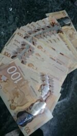 Stack of fake Canadian hundred dollar bills arranged for display, showing the distinctive polymer design and holographic elements.