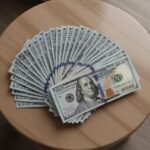 Professional counterfeit hundred dollar bills arranged in a fan pattern, highlighting detailed engraving and color-shifting ink.