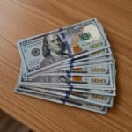 Close-up of high-quality counterfeit $100 bills with Benjamin Franklin portrait, showing realistic security features for sale online.