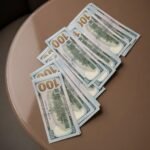 Stack of fake USD currency notes displaying authentic watermarks and holographic strips, marketed as undetectable counterfeit money.