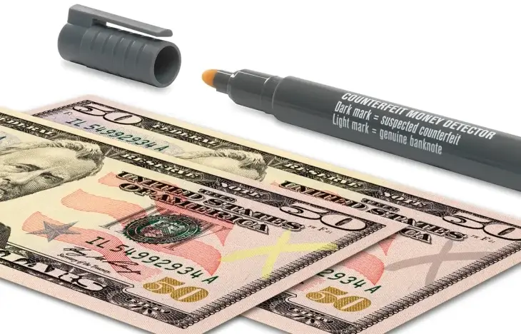 A counterfeit pen leaving a clear mark on genuine currency.